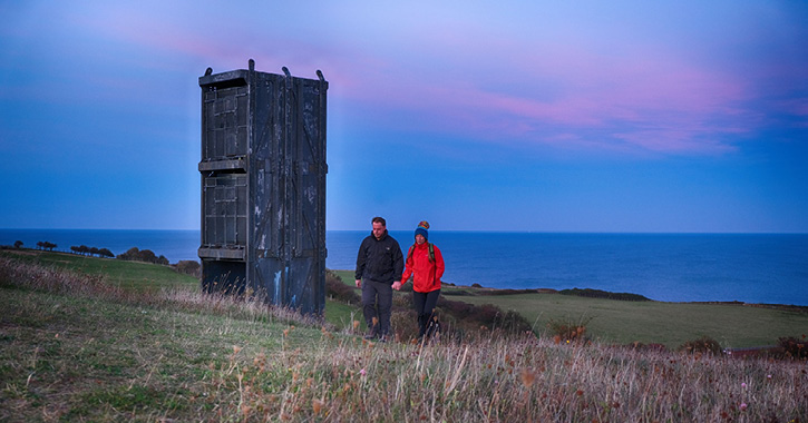 Couple walking past Easington Colliery pit cage memorial 